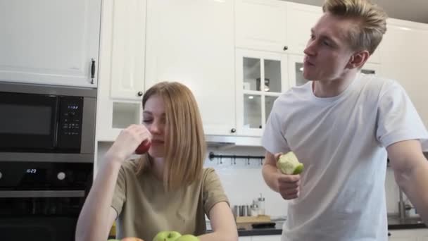 Een paar in de keuken. Groene appels eten. — Stockvideo