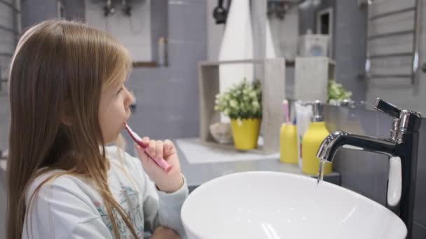 Ein kleines Mädchen putzt sich die Zähne. Früh morgens. — Stockvideo