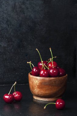 Siyah arka planda kirazlar ahşap kasede.