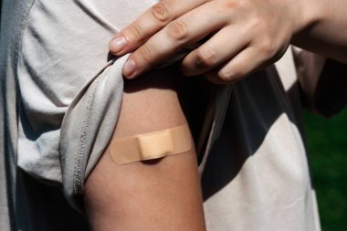 Omzunda yara bandı olan bir kadın eli