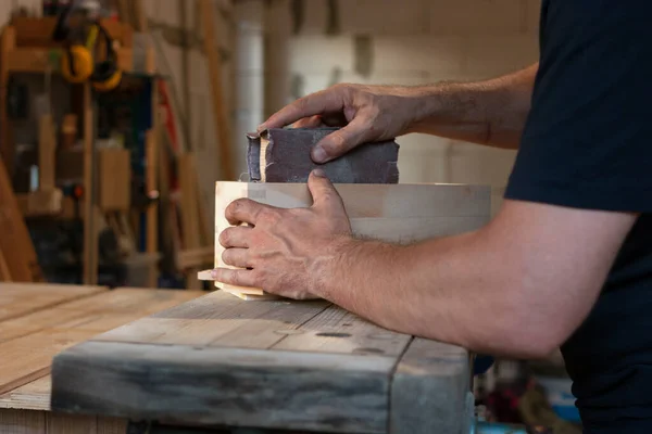 Marangoz ahşap kutuyu zımparalıyor.