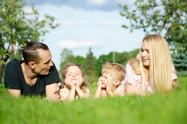 A boldog szülők-gyerekek a parkban fekvő portré — Stock Fotó