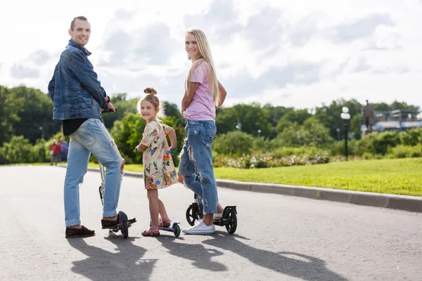 Familie met scooters in het park — Stockfoto