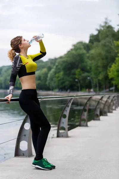 Sportswoman drinking water after running — Stock Photo, Image