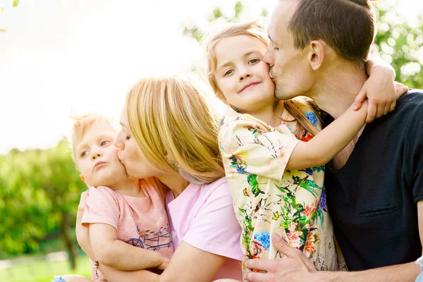 Glad familj på fyra kyssas utanför. — Stockfoto