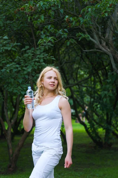 Девочка гуляет в парке и пьет воду — стоковое фото