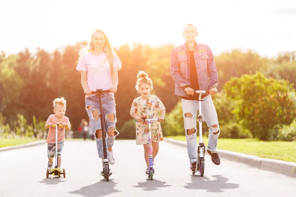 Family with scooters in the park — Stock Photo, Image