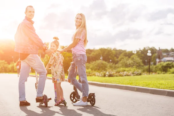 Familj med skotrar i parken — Stockfoto