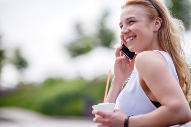 Milkshake ve cep telefonu açık havada üzerinde konuşmaya olan kadın