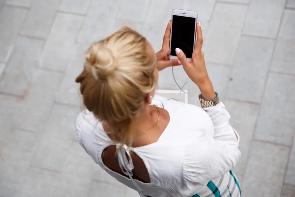 La chica tiene un teléfono móvil en sus manos . — Foto de Stock