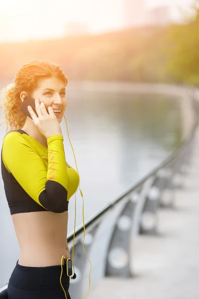 Счастливая спортивная девушка разговаривает по телефону в парке — стоковое фото