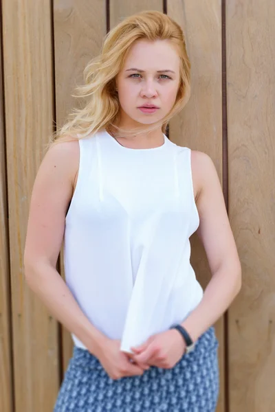 Módní blond žena v bílé halence na dřevěné stěně obrazce pozadí — Stock fotografie