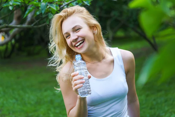 Веселая блондинка с бутылкой воды — стоковое фото
