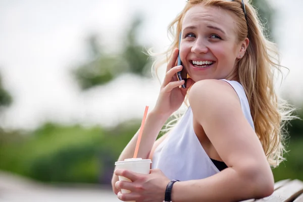 Nette blonde Frau im Freien telefoniert und lacht — Stockfoto