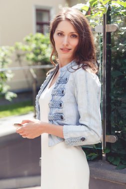 Sokak arka plan üzerinde kahverengi saçlı şık genç kadın