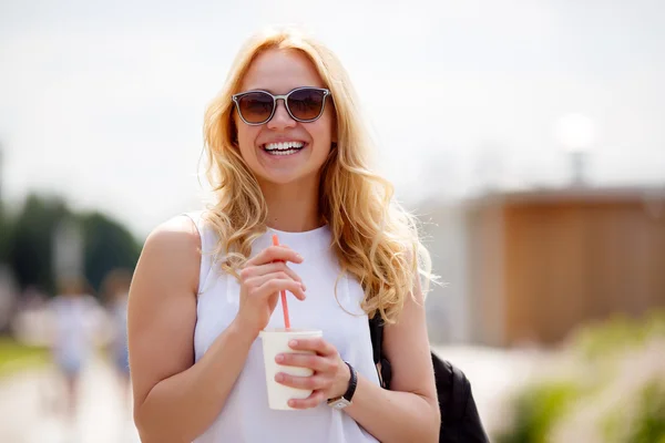 Portrét blondýnka s zářivým úsměvem na rozmazané pozadí — Stock fotografie