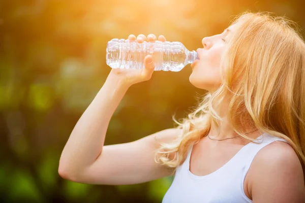 Блондинка пьет воду из бутылки в жаркий солнечный день — стоковое фото