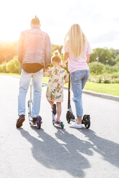 Family with scooters in the park — Stock Photo, Image