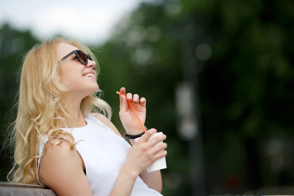 Kavkazská dívka s kudrnaté blond vlasy, podíváme se v sluneční brýle — Stock fotografie