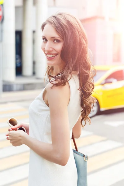 Beautiful young brunette woman in white dress on crosswalk background — Stock Photo, Image