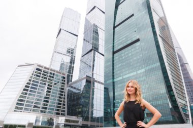 Gökdelenler arka plan üzerinde siyah elbiseli çekici sarışın kadın