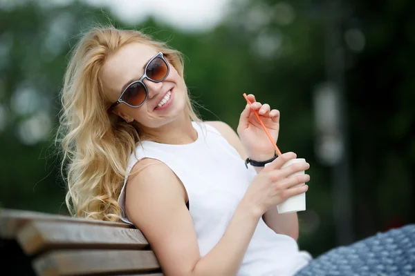 Blondynka z milkshake sobie okulary w parku — Zdjęcie stockowe