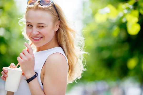 Cute winking blond woman with milkshake — Stock Photo, Image