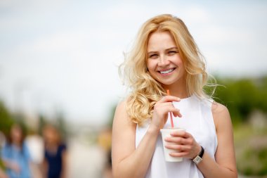Gülümseyen ve kameraya bakarak içki, tutan genç kadın