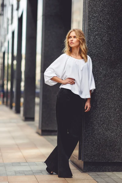 Young pensive business lady in white blouse and black pants — Stock Photo, Image