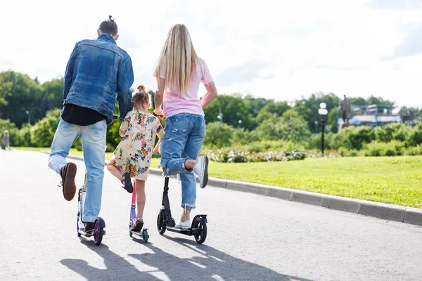 Familie met scooters in het park — Stockfoto