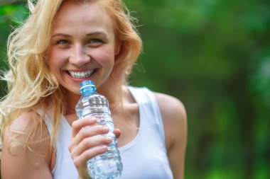 Plastik şişe su tutarak sevimli sarışın kız