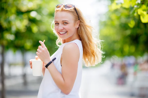 Cute blonde holding milkshake and showing tongue — Stock Photo, Image