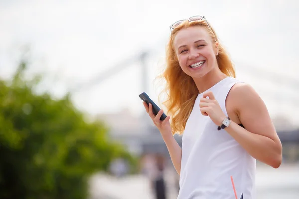 Portrait of smiling girl with curly hair holding smartphone — Stock Photo, Image