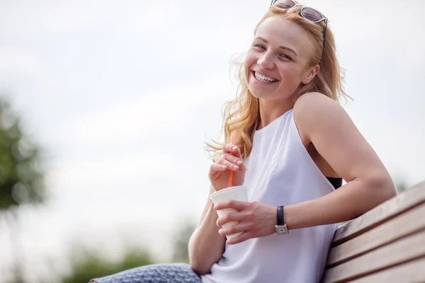 Porträt glücklicher Mädchen, die mit Getränken auf Bank sitzen — Stockfoto