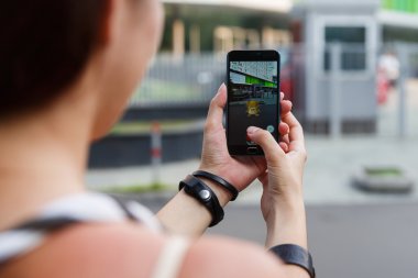 Adam onun perde Pokemon Go uygulaması ile gösterilen bir elinde telefon düzenlenen.