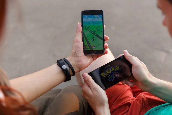 Első ember telefon mutatja a képernyő-val Pokemon Go app, kezében tartott második telepítése az alkalmazás. — Stock Fotó