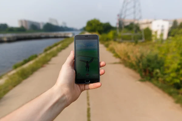 Hombre sostuvo el teléfono en una mano mostrando su pantalla con la aplicación Pokemon Go . — Foto de Stock