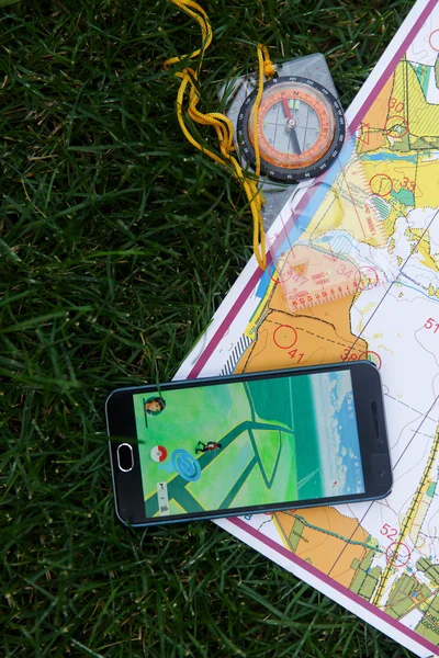 Teléfono con aplicación Pokemon Go en pantalla, mapas y compas . — Foto de Stock