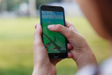 Adam onun perde Pokemon Go uygulaması ile gösterilen bir elinde telefon düzenlenen.