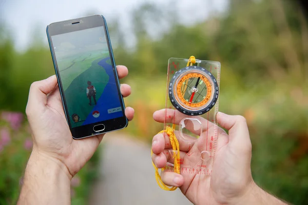 Man höll i händerna Compas och telefon som visar sin skärm med Pokemon go ansökan. — Stockfoto