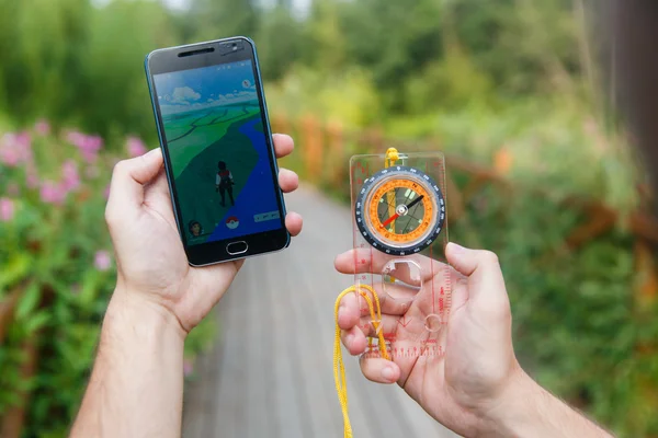 Man höll i händerna Compas och telefon som visar sin skärm med Pokemon go ansökan. — Stockfoto
