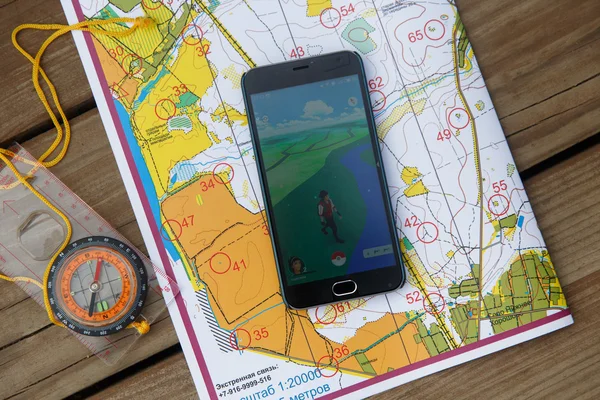Compas y pantalla del teléfono con aplicación Pokemon Go en los mapas . — Foto de Stock