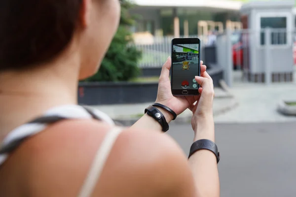 Man gehouden telefoon in de ene hand tonen van zijn scherm met Pokemon Go toepassing. — Stockfoto