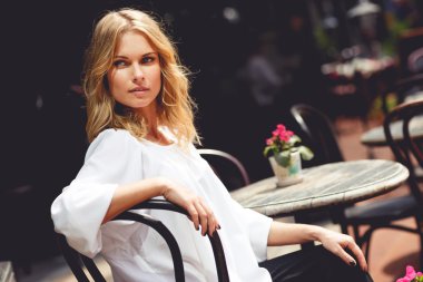 Güneşli günde açık kafede oturan güzel sarışın Bayan