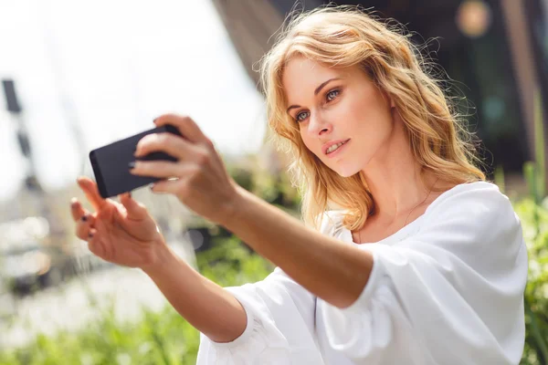 Young beautiful blonde woman photographed themselves on mobile phone — Stock Photo, Image