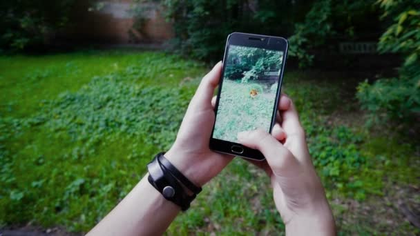 Mujer jugando Pokemon GO aplicación de la aplicación de teléfono inteligente de realidad aumentada de éxito al intentar atrapar Pokemon Spearow . — Vídeos de Stock
