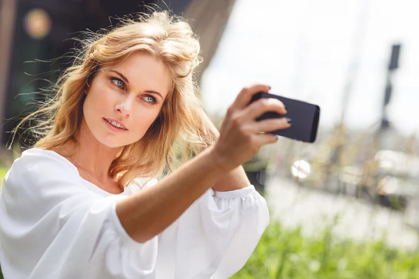 Beautiful blonde woman with natural makeup doing self portraits outdoors — Stock Photo, Image