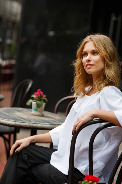 Młode ładne blond kobieta siedząc w kawiarni w ciągu dnia — Zdjęcie stockowe