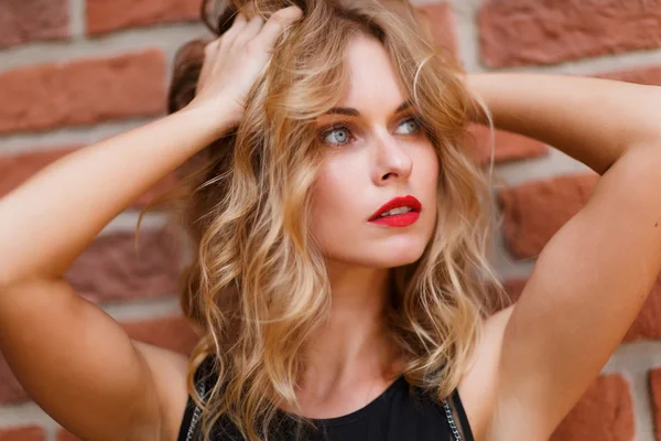 Красивая блондинка с серыми глазами на кирпичном фоне — стоковое фото