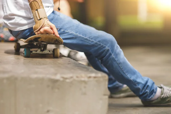 Uomo seduto nel parco sullo skateboard con protezione per le mani — Foto Stock